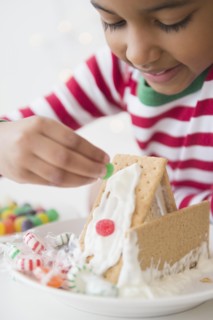 Mixed race girl decorating gingerbread house