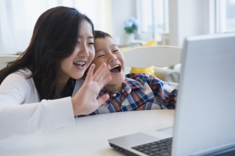 Brother and sister waving at video chat on computer
