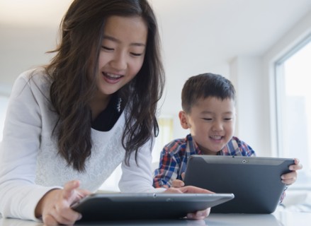 Asian brother and sister using digital tablets at table