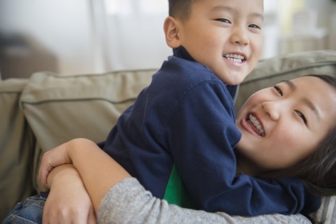 Asian brother and sister playing on sofa