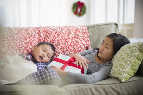 Asian brother and sister napping on sofa with Christmas gift