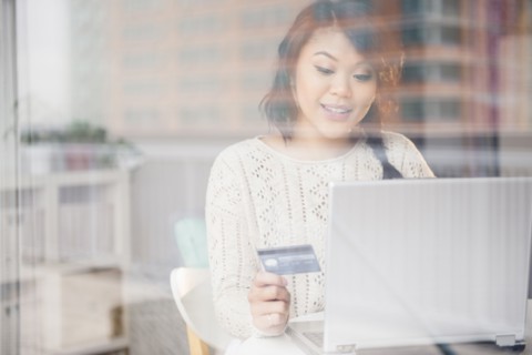 Pacific Islander woman shopping online on laptop behind window