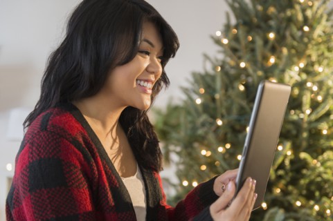 Pacific Islander woman using digital tablet near Christmas tree