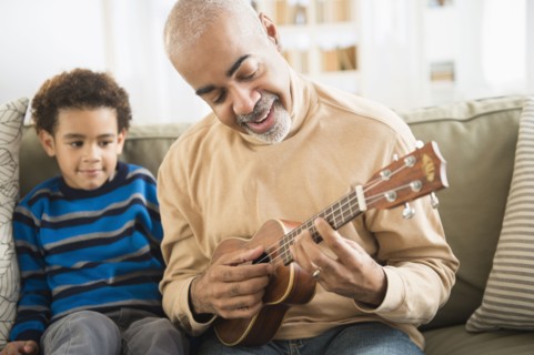 Mixed race grandfather and grandson playing ukulele