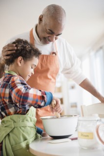 Mixed race grandfather and grandson baking in kitchen