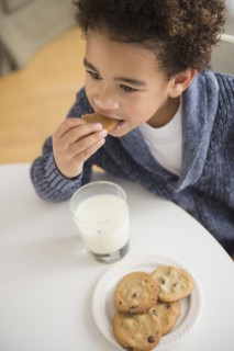 Mixed race boy eating cookies and milk