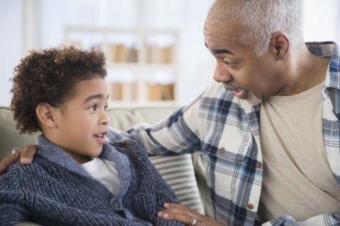 Mixed race grandfather and grandson talking on sofa