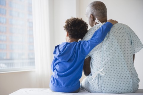 Mixed race grandfather sitting with grandson in hospital