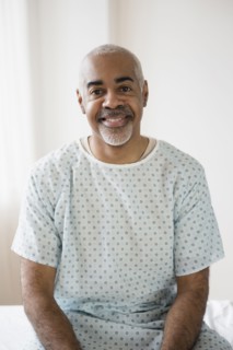Mixed race older man sitting on hospital bed