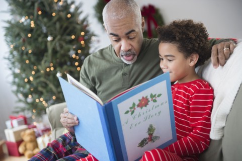 Mixed race grandfather reading to grandson at Christmas