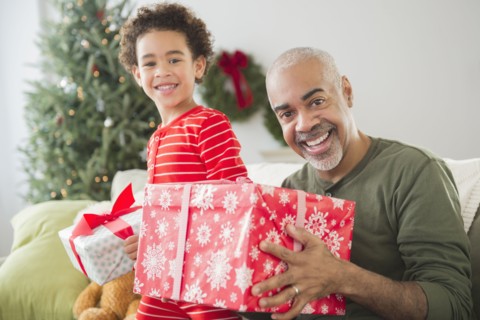 Mixed race grandfather and grandson opening Christmas gifts