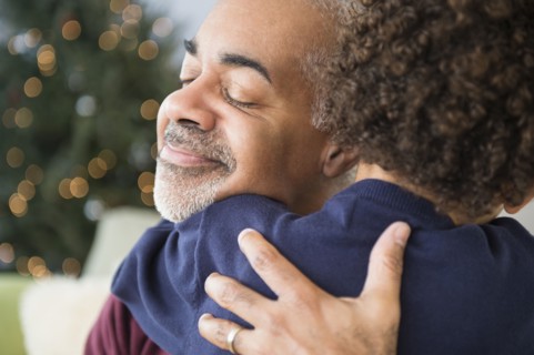 Mixed race grandfather and grandson hugging at Christmas