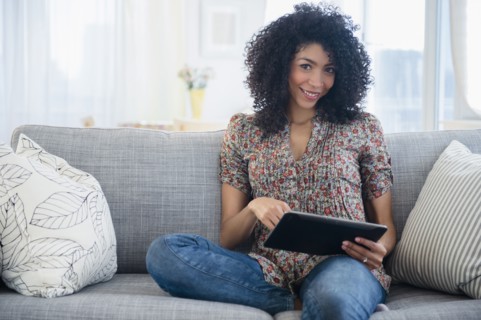 Mixed race woman using digital tablet on sofa
