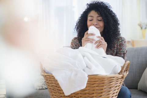 Mixed race woman smelling clean towels in laundry