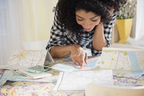 Mixed race woman planning road trip with maps