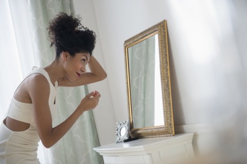 Mixed race woman styling hair in mirror