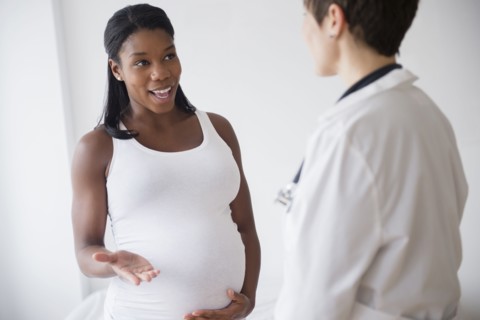Black pregnant woman talking to doctor