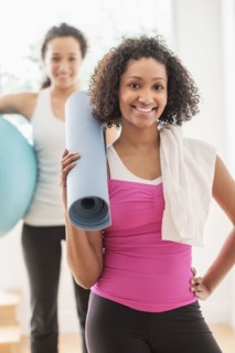 Woman carrying yoga mat in exercise class