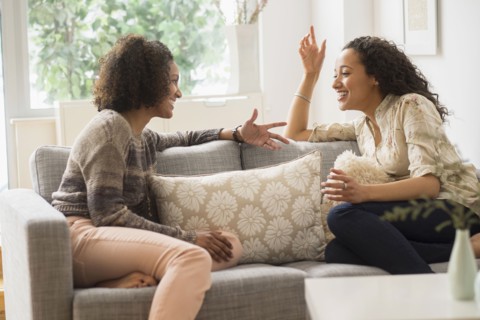 Laughing women talking on sofa