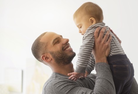 Smiling father playing with baby son