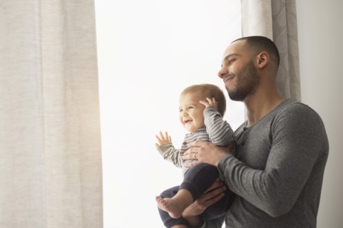 Smiling father and baby son looking out window