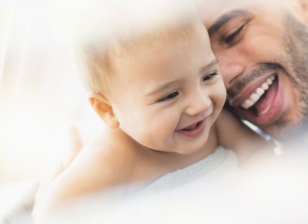 Father holding baby son in towel after bath