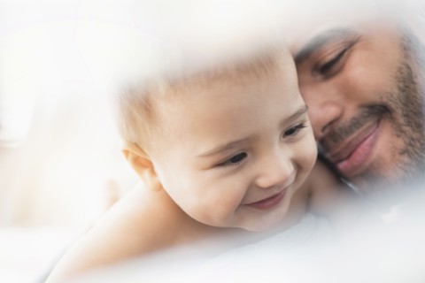 Father holding baby son in towel after bath