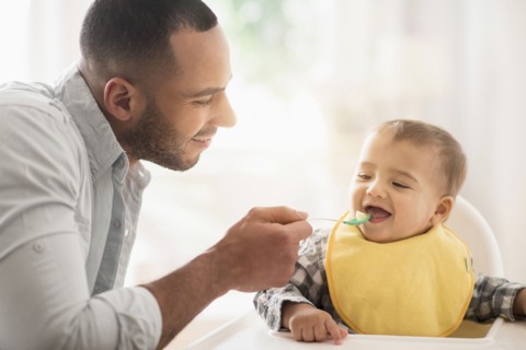Father feeding baby son in high chair