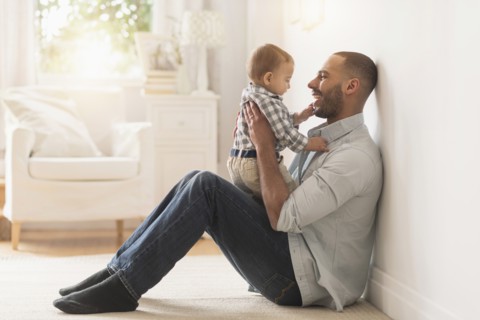Father playing with baby son on floor