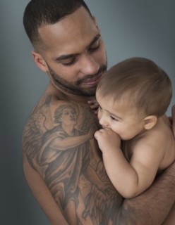 Father with tattoos holding baby son
