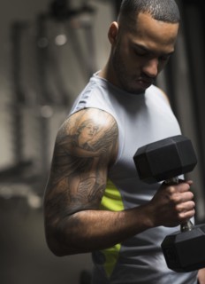Close up of Hispanic man lifting weights in gym