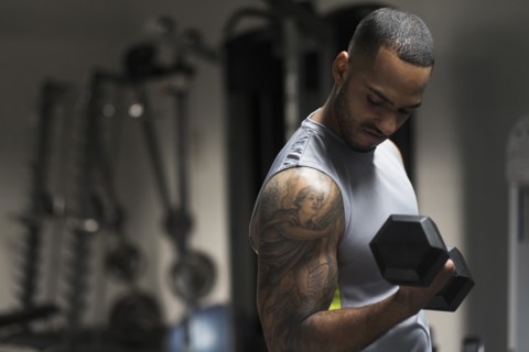 Close up of Hispanic man lifting weights in gym