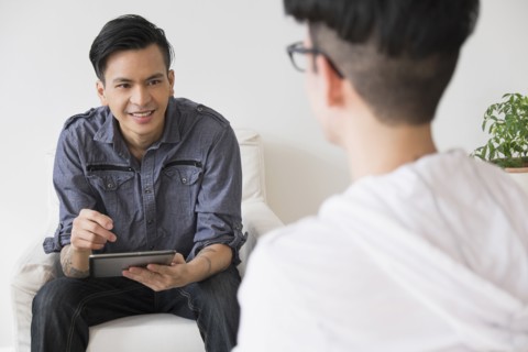 Men using digital tablet in living room