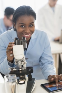 Scientist using microscope and digital tablet in research laboratory