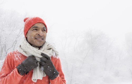 Black man wearing gloves and scarf in snow