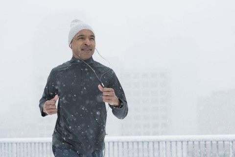 Black runner jogging in snow