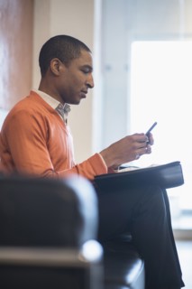 Black businessman using cell phone in office lobby