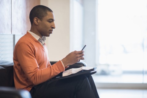 Black businessman using cell phone in office lobby
