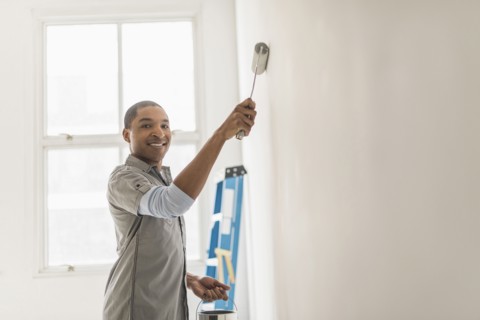 Black man painting wall of home