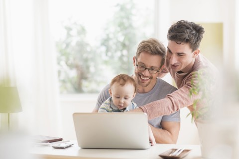 Caucasian gay fathers and baby using laptop