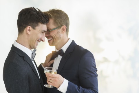 Caucasian gay grooms hugging at wedding