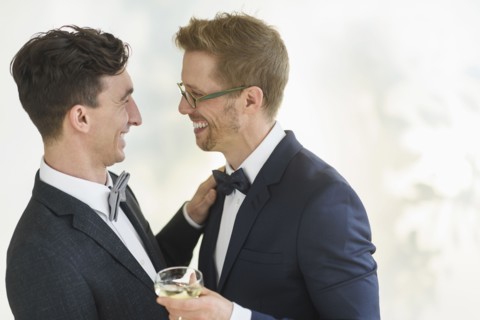 Caucasian gay grooms hugging at wedding