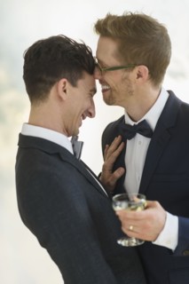 Caucasian gay grooms drinking champagne at wedding
