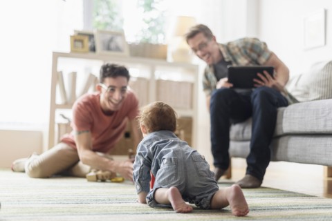 Caucasian gay fathers and baby relaxing in living room