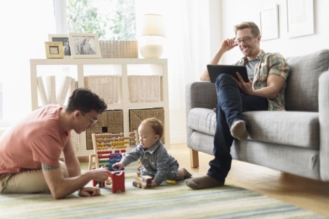 Caucasian gay fathers and baby relaxing in living room
