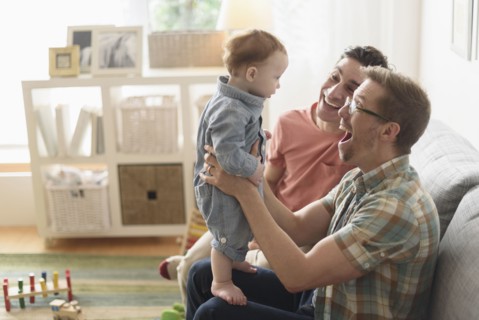 Caucasian gay fathers and baby playing in living room