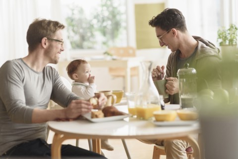 Caucasian gay fathers and baby eating breakfast