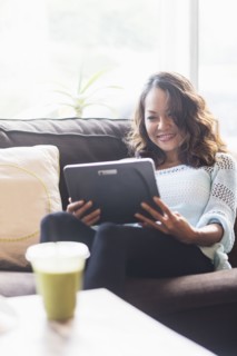 Chinese woman using digital tablet on sofa