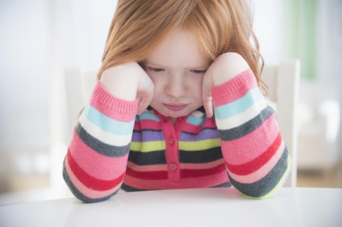 Caucasian girl crying at table