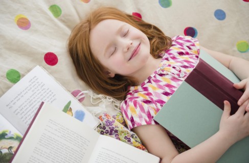 Caucasian girl reading books on bed